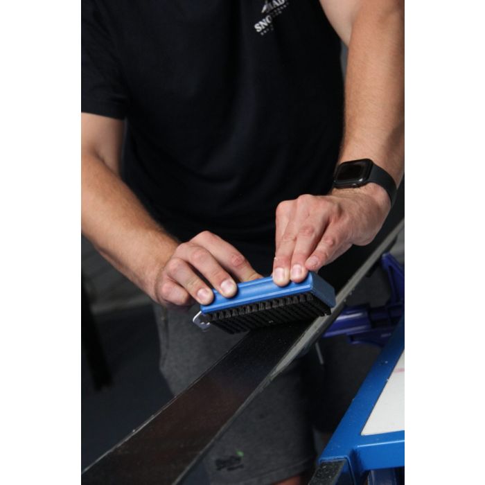 Waxen & Slijpen service: A technician expertly applying wax to a ski edge.